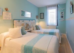 - 2 lits dans une chambre aux murs bleus dans l'établissement Apartamento Sueve 20, à Colunga