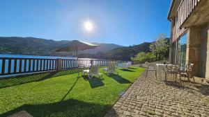 un patio con sillas y una sombrilla en el césped en A Cabana, en Gerês