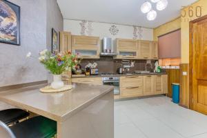 une cuisine avec des placards en bois et un vase de fleurs sur un comptoir dans l'établissement Charming 2BR home in the heart of Marsaxlokk by 360 Estates, à Marsaxlokk