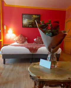 a bedroom with a bed with red walls and a table at Les Arcades Le Lion D'or in Buis-les-Baronnies