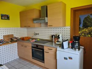 cocina con armarios de madera y nevera blanca en Ferienwohnung Eva, en Grebenhain