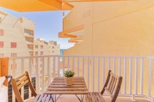 una mesa de madera con 2 sillas y una maceta en el balcón en LA PECERA - La Manga del Mar Menor - Edificio Mónaco - Kilómetro 7 - cama plegable y sofá-cama, en La Manga del Mar Menor