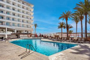 a swimming pool in front of a hotel with palm trees at Hotel Vibra Algarb in Playa d'en Bossa