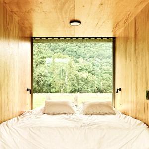 a bed in a room with a large window at Clareira Cabanas in Gonçalves