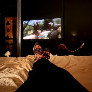 a person laying on a bed watching a tv at Clareira Cabanas in Gonçalves +46 photos