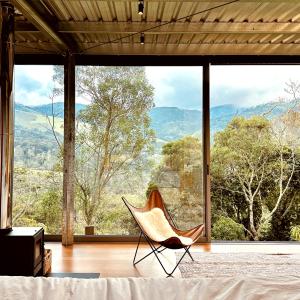 a room with a chair in front of a large window at Clareira Cabanas in Gonçalves