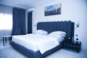 a bedroom with a large bed with a blue headboard at Summerset Continental Hotel Maitama in Abuja