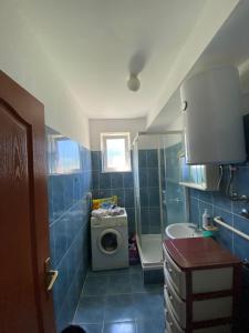 a blue tiled bathroom with a washing machine and a sink at Apartments TEA in Trebinje