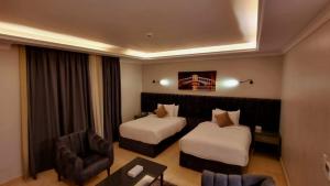 una habitación de hotel con 2 camas y una silla en Grand Plaza 6 Octobar, en Qaryat ash Shamālī
