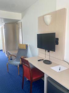 a room with a desk with a tv and a chair at Hotel Regina in Sankt Augustin