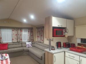 ein Wohnzimmer mit einem Sofa und einer Küche in der Unterkunft Dog Friendly 8 Berth Caravan At Dovercourt Holiday Park In Essex Ref 44004p in Great Oakley