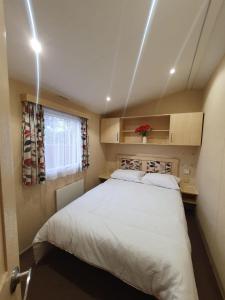 ein Schlafzimmer mit einem großen weißen Bett und einem Fenster in der Unterkunft Dog Friendly 8 Berth Caravan At Dovercourt Holiday Park In Essex Ref 44004p in Great Oakley