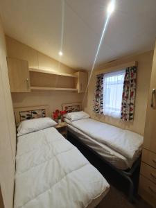 2 Betten in einem kleinen Zimmer mit Fenster in der Unterkunft Dog Friendly 8 Berth Caravan At Dovercourt Holiday Park In Essex Ref 44004p in Great Oakley