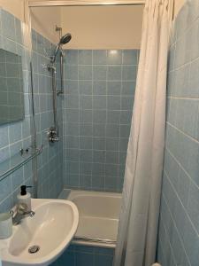 uma casa de banho em azulejos azuis com um lavatório e um chuveiro em La Bella em Garrel