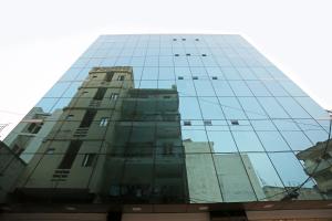 un edificio de cristal alto reflejado en las ventanas en OYO Flagship M SUITES, en Nueva Delhi