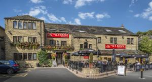 um restaurante com mesas e guarda-sóis em frente a um edifício em The Old Bridge Inn, Holmfirth, West Yorkshire em Holmfirth