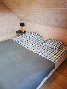 a bed in a room with a wooden wall at Stilove Wydmy in Sasino