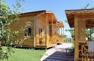 a wooden house with a deck in a yard at Şahan Bungalov in Gökçe