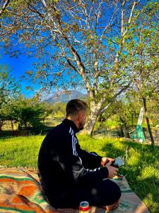 BIO FARMA في تيرانا: رجل يجلس على بطانية في العشب