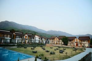 a resort with a pool and some buildings and mountains at Evara Spa & Resort in Rāmnagar