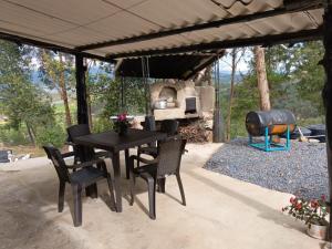 eine Terrasse mit einem Tisch, Stühlen und einem Grill in der Unterkunft Alojamiento en cabaña in Fúquene