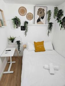 a white bedroom with a bed and a table and plants at Habitación Callao in Madrid