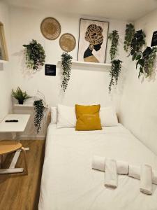Un dormitorio con una cama blanca con plantas en la pared en Habitación Callao, en Madrid