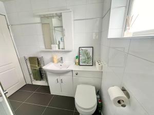 a white bathroom with a toilet and a sink at Ideal 3 Bed Home In Glasgow City With Free Parking in Glasgow