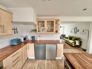 a kitchen with stainless steel appliances and a living room at Ideal 3 Bed Home In Glasgow City With Free Parking in Glasgow