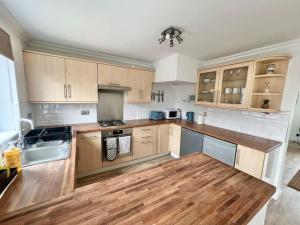 a kitchen with wooden cabinets and a wooden floor at Ideal 3 Bed Home In Glasgow City With Free Parking in Glasgow