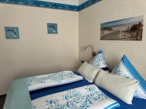 a bed with blue and white sheets and pillows at Haus Troja in Warnemünde