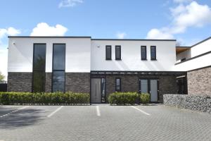 a white house with black windows and a parking lot at Villa met 13 slaap plaatsen in Alphen