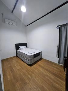 - une chambre avec un lit dans une pièce dotée de parquet dans l'établissement IM Merapi Homestay, à Ngaglik