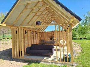 a wooden gazebo with a couch and a table at Domek w Górach Izerskich 4 i 6 osobowy, agroturystyka, żywe zwierzęta, w pełni wyposażone, plac zabaw dla dzieci, ognisko z kijkami i rusztem, ogrzewanie i klimatyzacja, latem basen in Mirsk