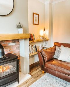 a living room with a leather couch and a fireplace at Olive Holiday Cottage Matlock in Matlock Bank