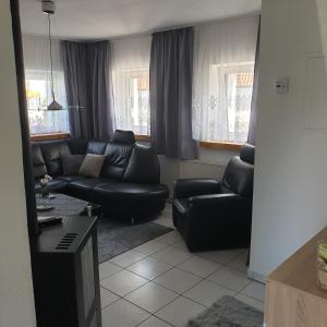 una sala de estar con un sofá de cuero negro y sillas en Ehemaliger Bauernhof en Gunzenhausen