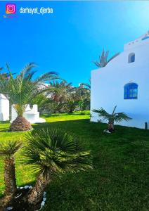 a yard with palm trees and a white building at Dar hayat in Djerba