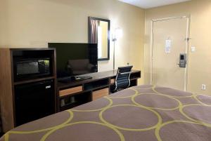 a hotel room with a bed and a desk and a television at Super 8 by Wyndham Lafayette in Lafayette