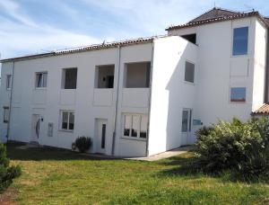 ein weißes Gebäude mit Fenstern und einem Grasfeld in der Unterkunft Apartment with garden in Barbariga in Barbariga
