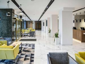a lobby of a building with yellow chairs and tables at Mercure Opole in Opole
