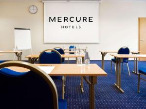 a conference room with tables and chairs and a whiteboard at Mercure Opole in Opole