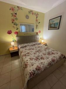 1 dormitorio con 1 cama con flores en la pared en Belvedere Lacinio -Casa Vacanze-Villaggio Casarossa, en Crotone