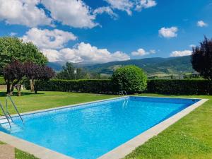 a swimming pool in a garden with mountains in the background at Dúplex a Age amb piscina in Puigcerdà