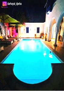 una piscina iluminada por la noche con luces azules en Dar hayat, en Djerba