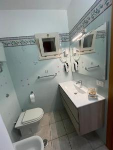 Baño blanco con aseo y lavamanos en Belvedere Lacinio -Casa Vacanze-Villaggio Casarossa, en Crotone