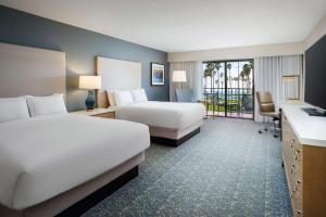 a hotel room with two beds and a balcony at Hilton Santa Barbara Beachfront Resort in Santa Barbara