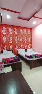 twee bedden in een kamer met een rode muur bij Hotel Atithi Galaxy in Kānpur