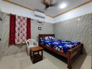 - une chambre avec un lit, une chaise et des rideaux dans l'établissement SIVA LODGE, à Rameswaram