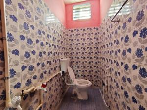 a bathroom with a toilet with blue and white tiles at SIVA LODGE in Rāmeswaram