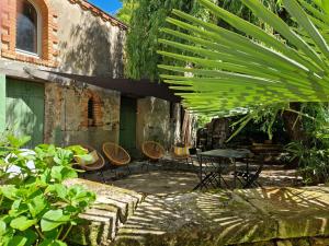 Un patio con una mesa y sillas debajo de un árbol. en Le jardin aux camélias, en La Roche-sur-Yon